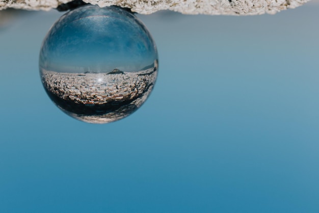 Foto close-up di una palla di cristallo capovolta con riflesso contro un cielo limpido