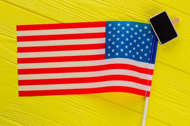 Close up us flag and black board top view. yellow wooden table on the background