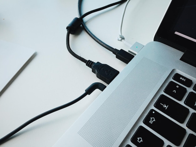 Photo close-up of usb cables attached to laptop on table