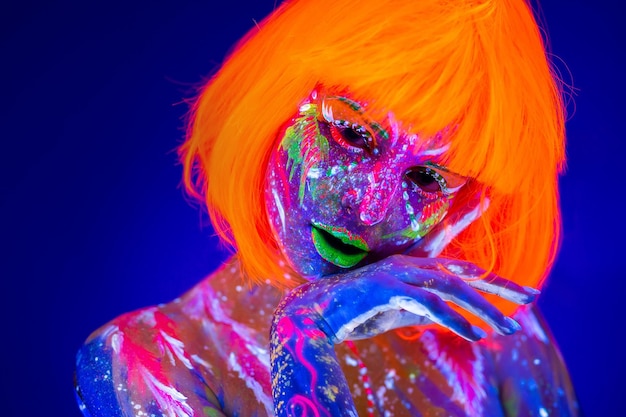 Close up UV portrait of a female model with artistic colorful makeup and orange wig with closed