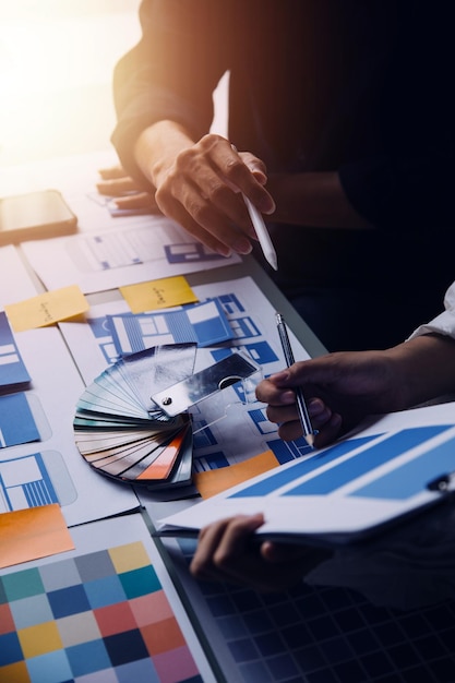 Close up ux developer and ui designer brainstorming about mobile app interface wireframe design on table with customer breif and color code at modern officeCreative digital development agency