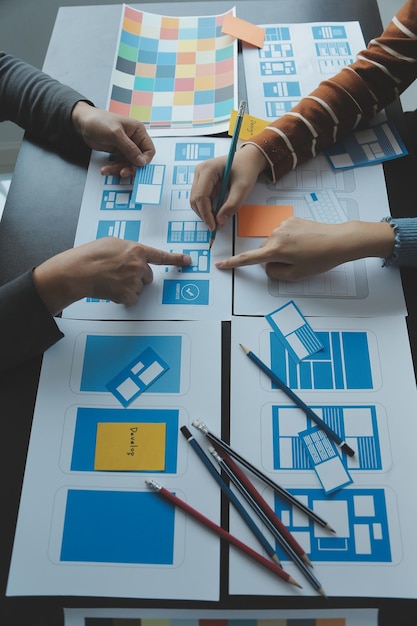 Close up ux developer and ui designer brainstorming about mobile app interface wireframe design on table with customer breif and color code at modern officeCreative digital development agency