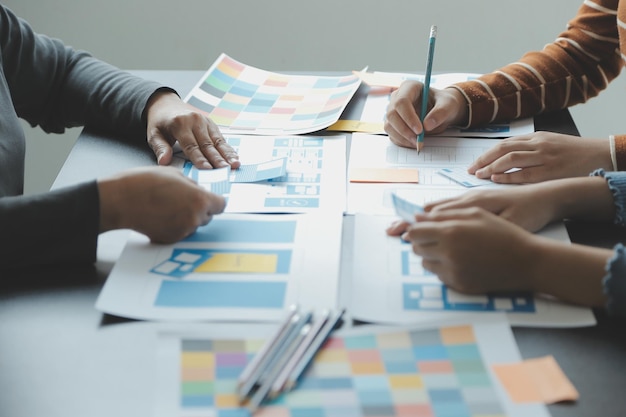 Close up ux developer and ui designer brainstorming about mobile app interface wireframe design on table with customer breif and color code at modern officeCreative digital development agency