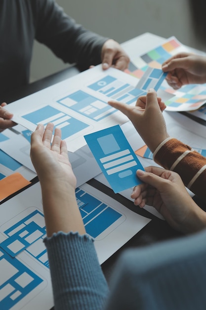 Close up ux developer and ui designer brainstorming about mobile app interface wireframe design on table with customer breif and color code at modern officeCreative digital development agency