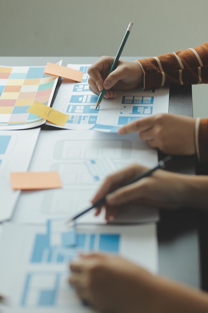 Close up ux developer and ui designer brainstorming about mobile app interface wireframe design on table with customer breif and color code at modern officeCreative digital development agency