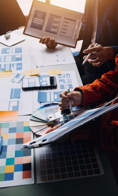 Close up ux developer and ui designer brainstorming about mobile app interface wireframe design on table with customer breif and color code at modern officeCreative digital development agency