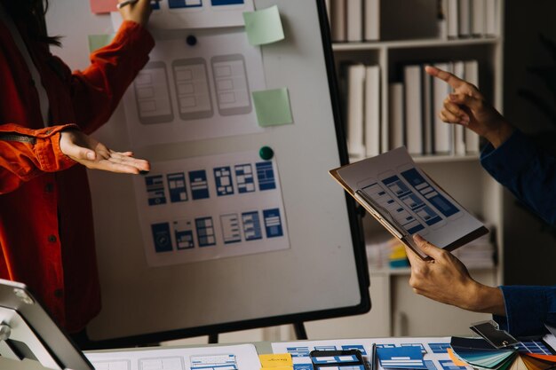 Close up ux developer and ui designer brainstorming about mobile app interface wireframe design on table with customer breif and color code at modern officeCreative digital development agency