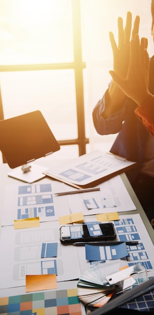 Close up ux developer and ui designer brainstorming about mobile app interface wireframe design on table with customer breif and color code at modern officeCreative digital development agency