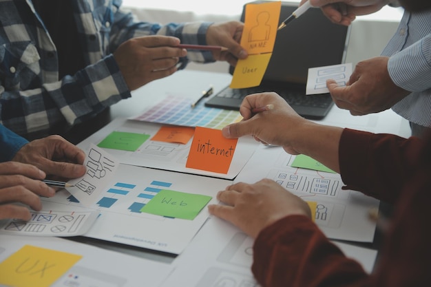 Close up ux developer and ui designer brainstorming about mobile app interface wireframe design on table with customer breif and color code at modern officeCreative digital development agency