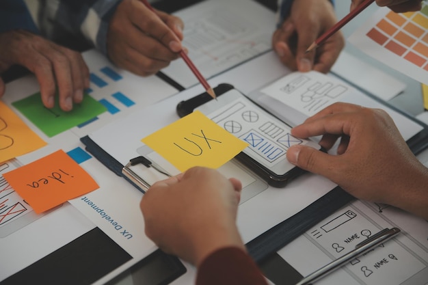 Close up ux developer and ui designer brainstorming about mobile app interface wireframe design on table with customer breif and color code at modern officeCreative digital development agency