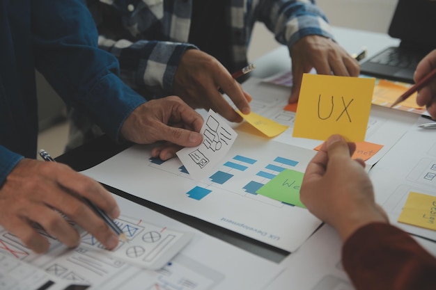 Close up ux developer and ui designer brainstorming about mobile app interface wireframe design on table with customer breif and color code at modern officeCreative digital development agency