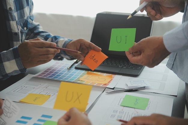 Close up ux developer and ui designer brainstorming about mobile app interface wireframe design on table with customer breif and color code at modern officeCreative digital development agency