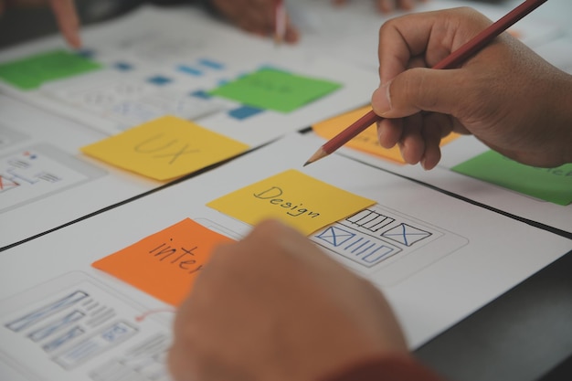 Photo close up ux developer and ui designer brainstorming about mobile app interface wireframe design on table with customer breif and color code at modern officecreative digital development agency