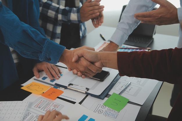 Close up ux developer and ui designer brainstorming about mobile app interface wireframe design on table with customer breif and color code at modern officeCreative digital development agency