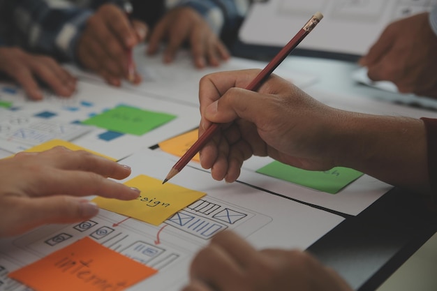 Photo close up ux developer and ui designer brainstorming about mobile app interface wireframe design on table with customer breif and color code at modern officecreative digital development agency