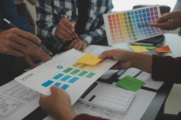 Close up ux developer and ui designer brainstorming about mobile app interface wireframe design on table with customer breif and color code at modern officeCreative digital development agency