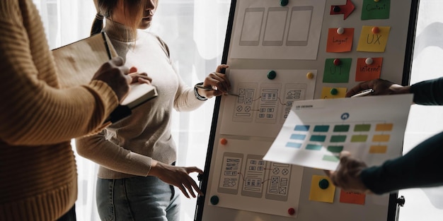 Close up ux developer and ui designer brainstorming about mobile app interface wireframe design on table with customer breif and color code at modern officeCreative digital development agency