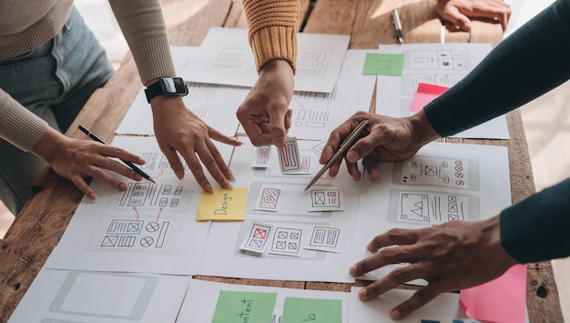 Close up ux developer and ui designer brainstorming about mobile app interface wireframe design on table with customer breif and color code at modern officeCreative digital development agency