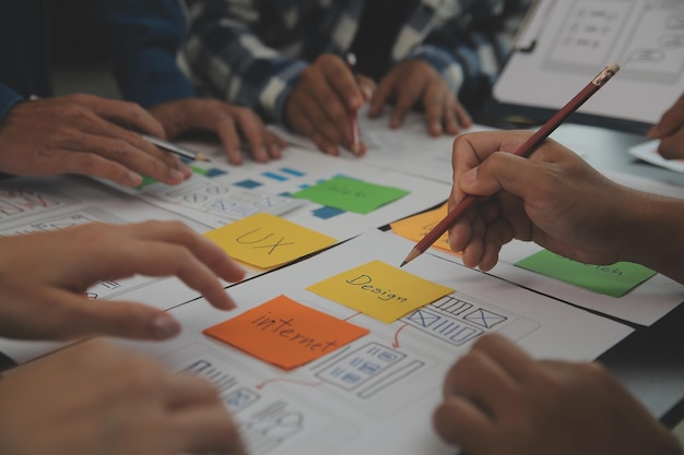 Close-up ux-ontwikkelaar en ui-ontwerper brainstormen over het draadframe-ontwerp van de mobiele app-interface op tafel met klantbreif en kleurcode bij modern kantoorCreatief digitaal ontwikkelingsbureau