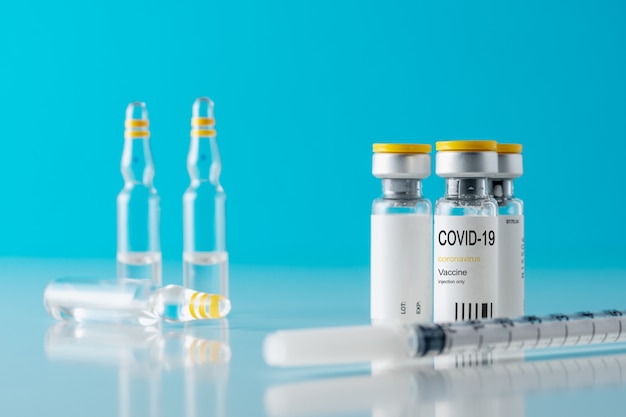 close up on vaccine serum in glass recipient with a syringe
