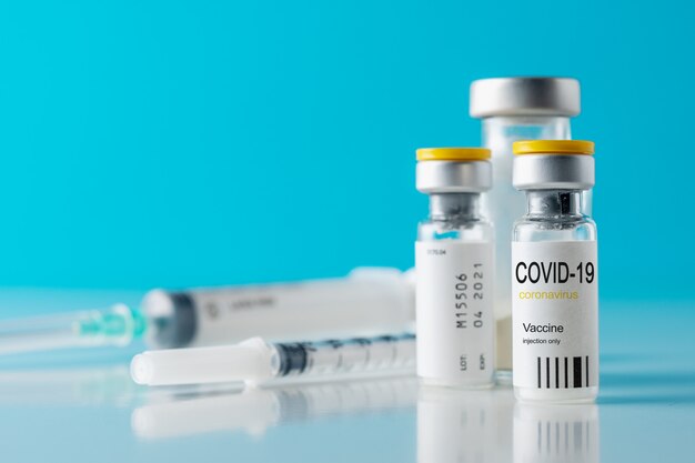close up on vaccine serum in glass recipient with a syringe