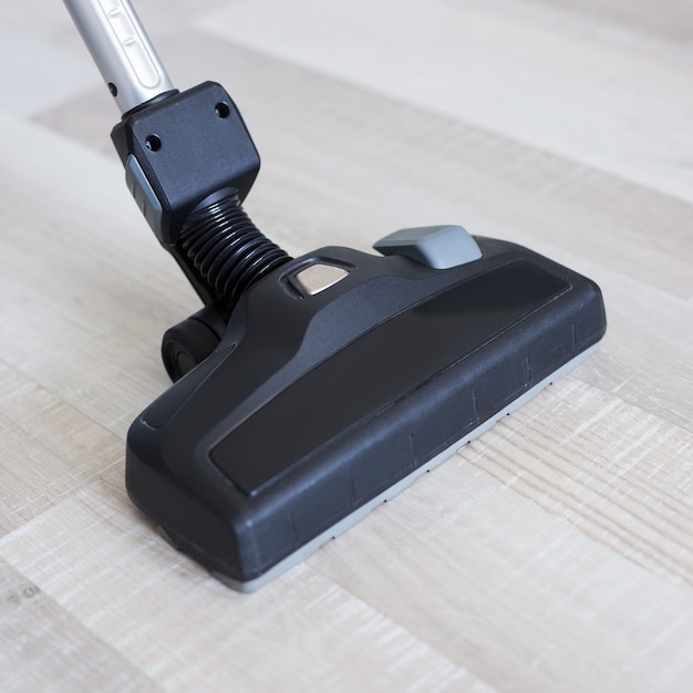 Close up of vacuum cleaner over wooden parquet floor background