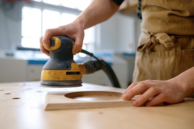 Close-up vakman handen werken met excentrische slijpmachine