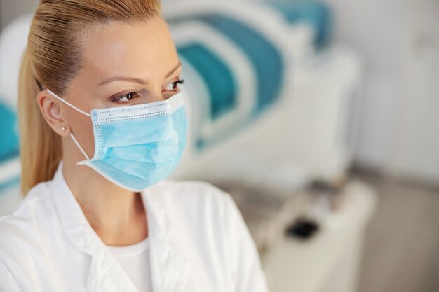 Close-up van aantrekkelijke vrouwelijke laboratoriumassistent die zich in laboratorium met beschermend masker op gezicht bevindt. Covid-uitbraak concept.