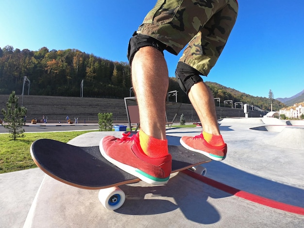 Close-up van actieve kerel die skateboard berijdt in skatepark