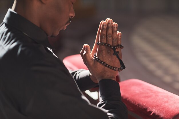 Close-up van Afrikaanse katholieken met rozenkrans kralen en bidden in de kerk