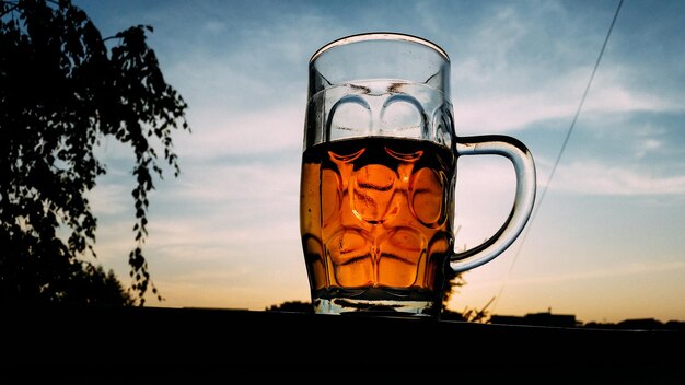 Close-up van alcoholische drank tegen de hemel tijdens zonsondergang