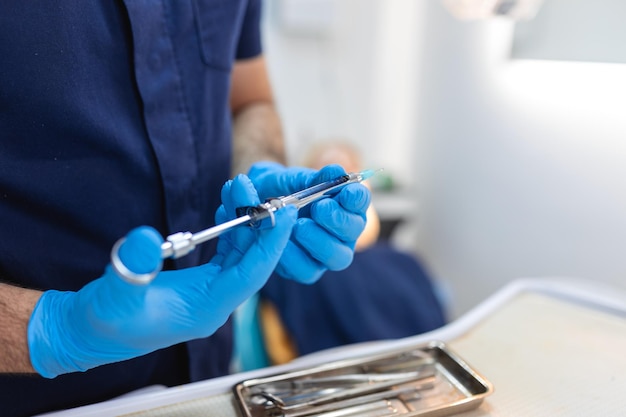 Close-up van anesthesiespuit in de handen van een tandarts-arts Anesthesist tandarts-arts houdt in zijn hand anesthesiespuit voorafgaand aan tandheelkundige ingrepen Dien een rubberen handschoen in
