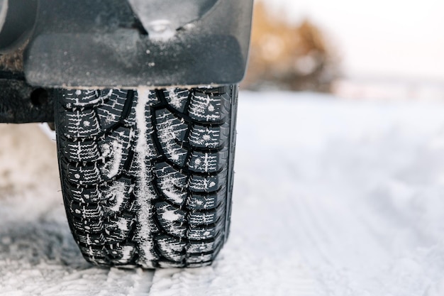 Close-up van autobanden in de winter op een bosweg bedekt met sneeuw