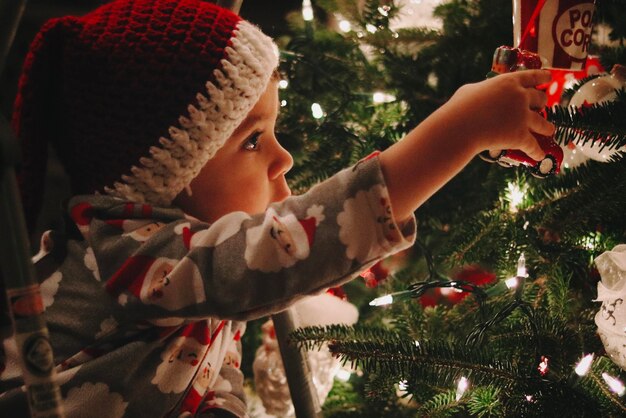 Foto close-up van baby meisje met kerstboom in de winter