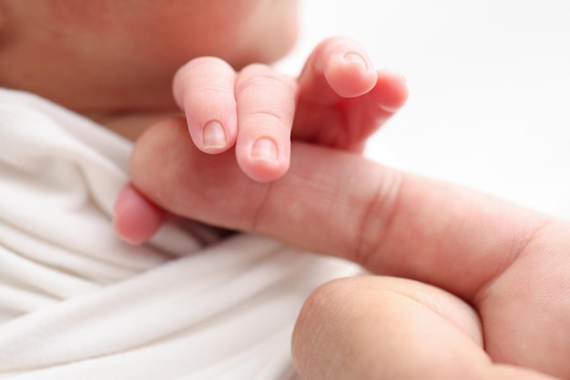 Foto close-up van baby's kleine hand hoofd oor en palm van moeder macro foto van pasgeboren baby na de geboorte die de vinger van de ouders stevig vasthoudt op witte achtergrond gezins- en thuisconcept gezondheidszorg pediatrie