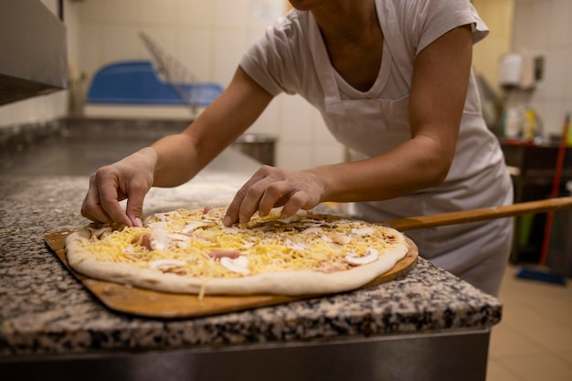 Foto close-up van bakker die pizzadeeg en topping klaarmaakt om te bakken