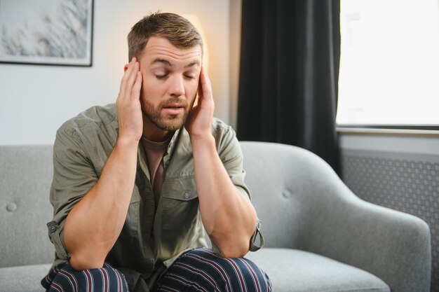 Foto close-up van bebaarde man van middelbare leeftijd die lijdt aan hoofdpijn thuis aanraken van zijn tempels panorama met kopie ruimte migraine hoofdpijn stress spanning probleem kater concept