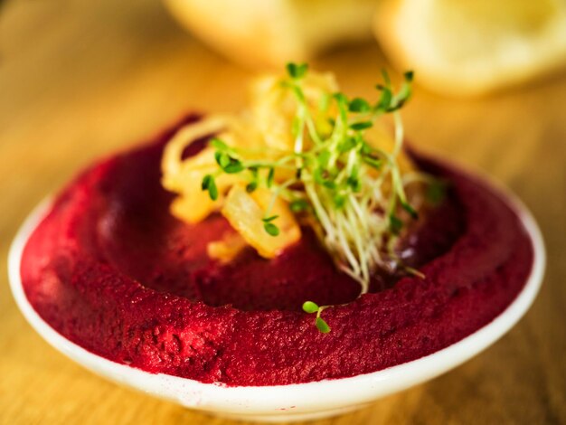 Foto close-up van beet hummus met spruiten in een schaal op een snijplank