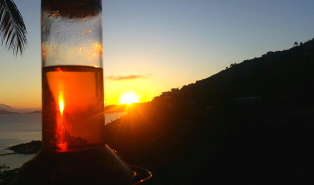 Foto close-up van bier in de zee tegen de hemel tijdens zonsondergang