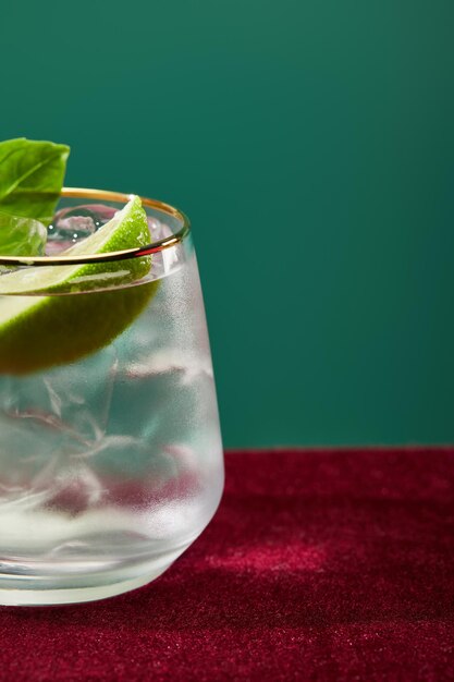 Close-up van bijgesneden glas met verfrissende mojito-munt en limoenschijfje geïsoleerd op groen