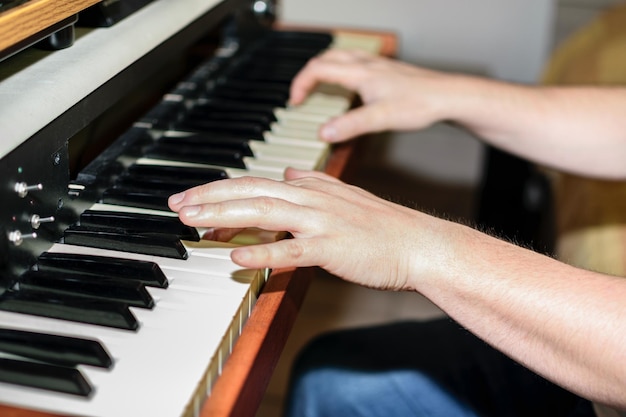Close-up van blanke handen die elektrische piano spelen in de slaapkamer