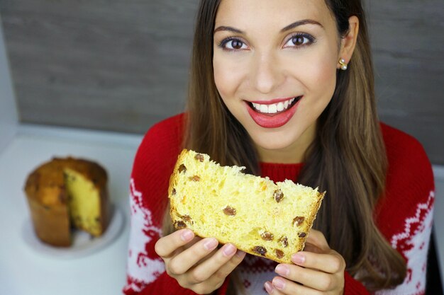 Close-up van bovenaf lachende jonge vrouw die een plakje panettone eet