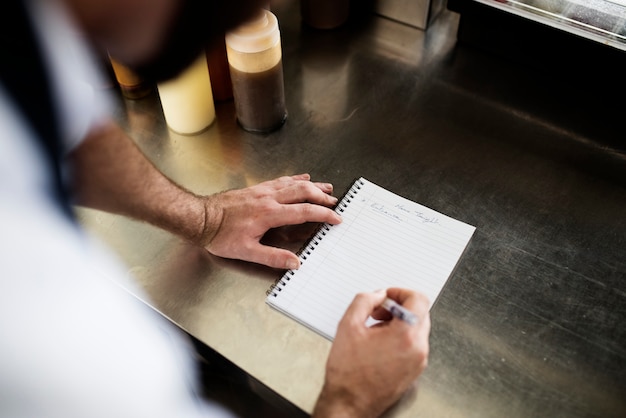 Close-up van chef-kok handschriftmenu op metaal kokende lijst