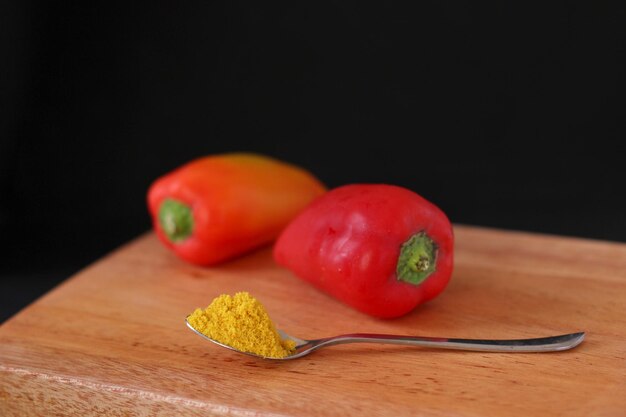 Foto close-up van chili pepers met specerijen tegen een zwarte achtergrond