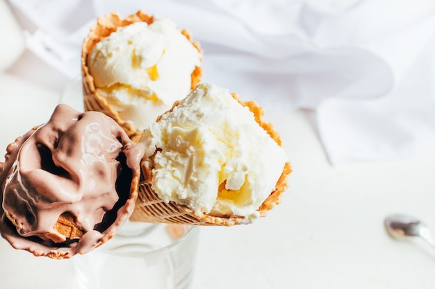 Close-up van chocolade en vanilleroomijs in wafelkoppen op witte achtergrond