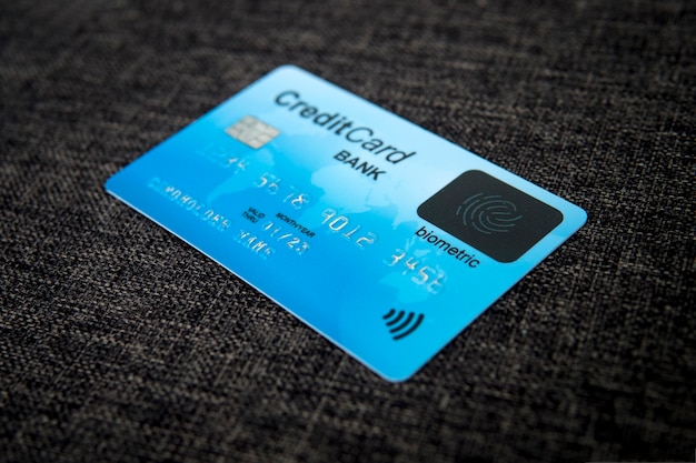 Close up van creditcard met nieuwe vingerafdruk technologie herkennen op zak materiële achtergrond. Kaart met elektronische chip, kaarthoudergegevens en biometrisch teken op zijn gezicht. Biometrie in het bankwezen.