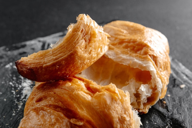 Foto close-up van croissants op een donkere achtergrond een croissant in stukjes gebroken verse en heerlijke fren