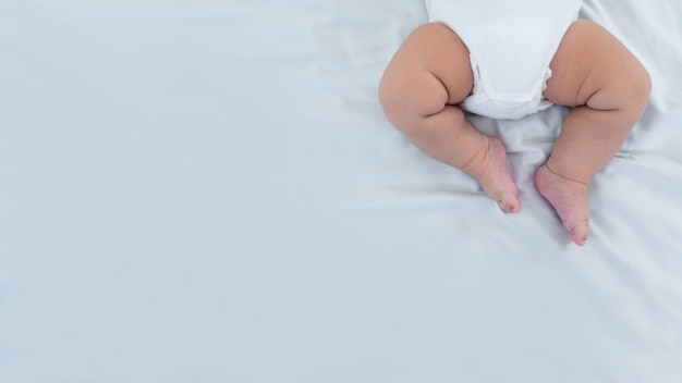 Close-up van de benen van de pasgeboren jongen op een witte bladachtergrond Baby slaapt op het bed