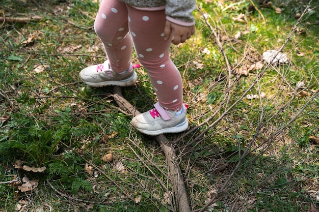 Close-up van de benen van het kindmeisje in het bos Wandelen met kinderen op het natuurpad buiten voor kinderen Gezondheid en sport van wandelaars