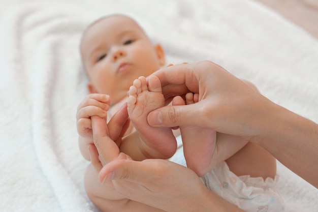 Close-up van de blote voeten van een pasgeboren baby in de handen van zijn moeder op een witte achtergrond
